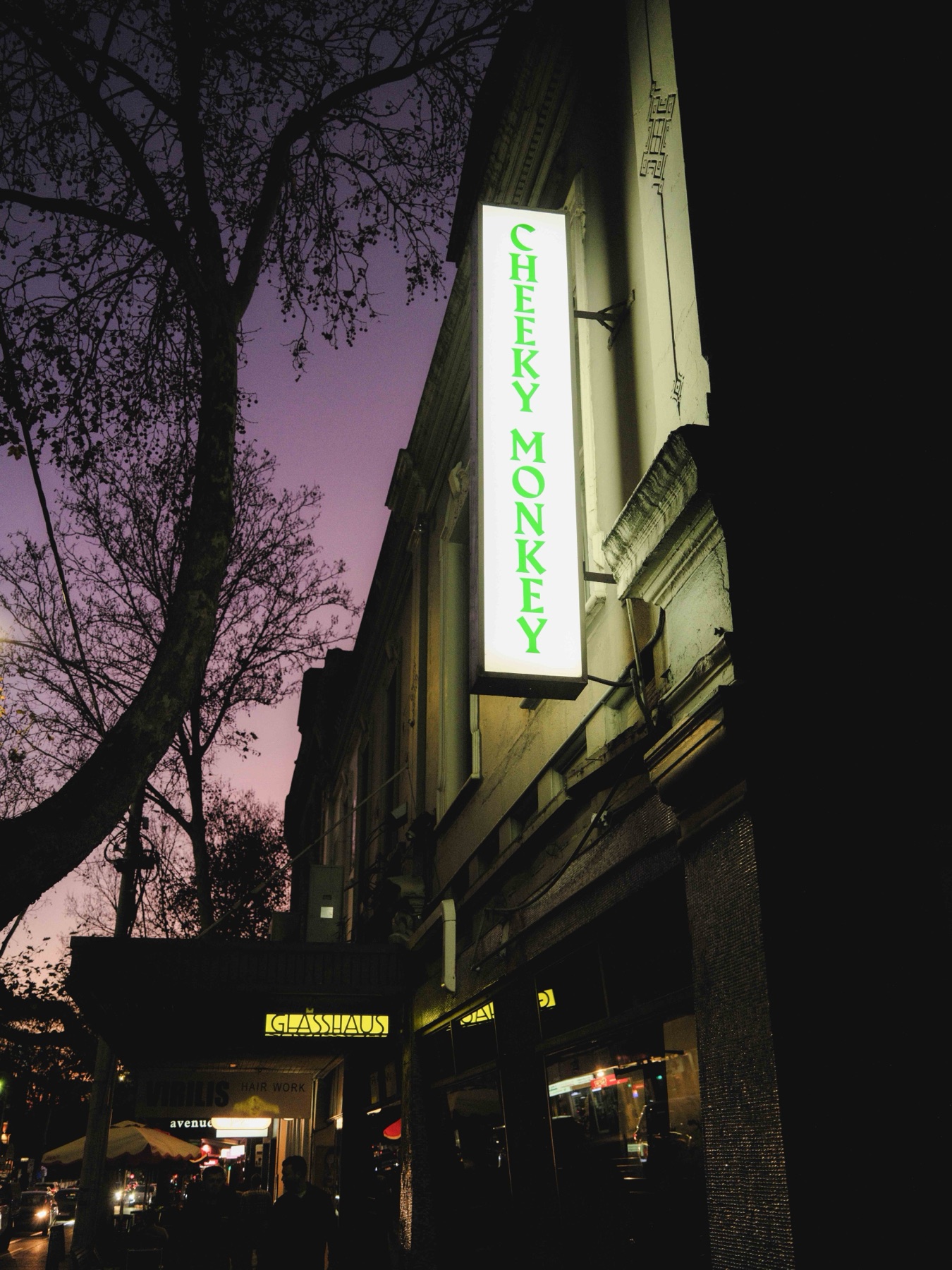 The Cheeky Monkey bar sign glowing at dusk on Swan Street, Richmond